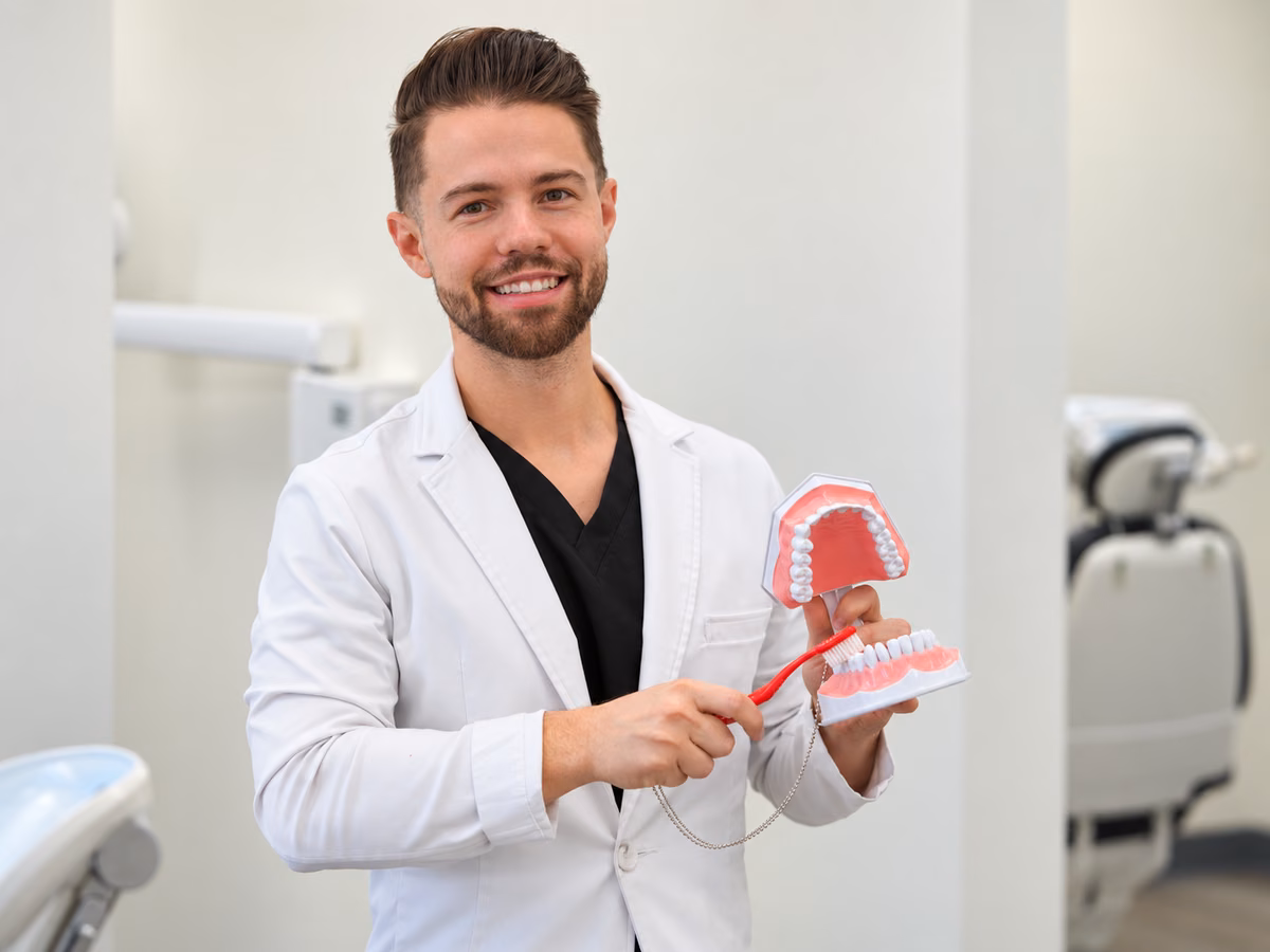 Dr. Christofer Hatzis holding a dental model and toothbrush at Byond Dental.